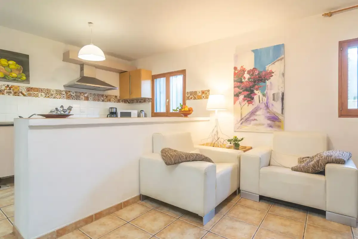 A bright kitchen and seating area with a counter and colorful wall art.