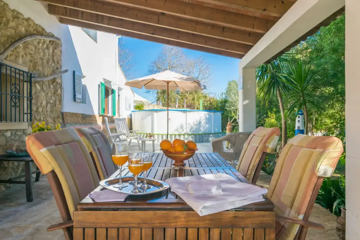 A covered outdoor patio has cushioned seating around a low table.