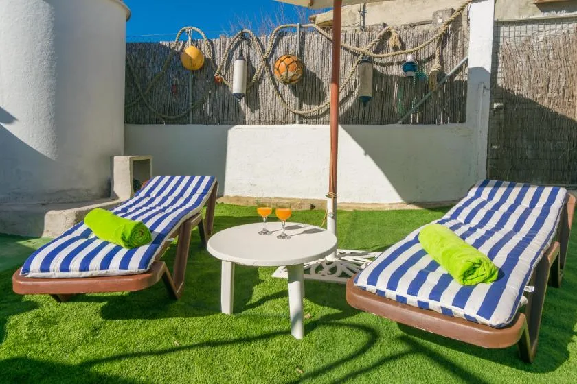 A sunny outdoor seating area with two striped loungers and a small round table.
