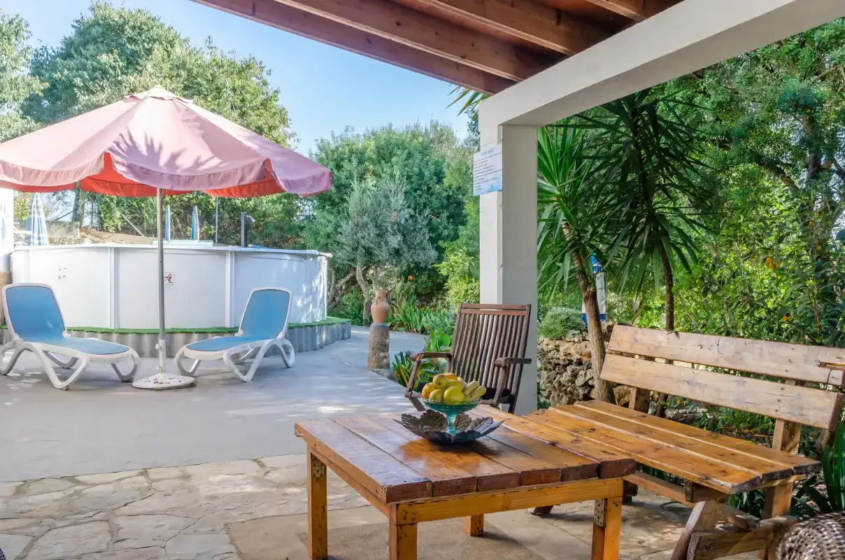 An outdoor patio with wooden seating and a shaded pool area.