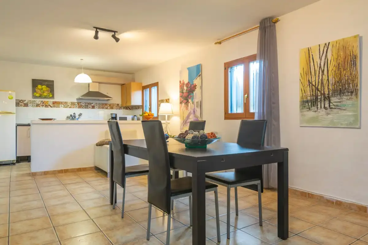 A dining area with a dark table and chairs beside an open kitchen.