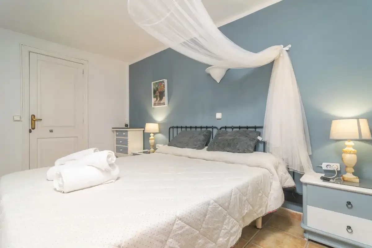 A bedroom with a white bed, blue walls, and bedside lamps.