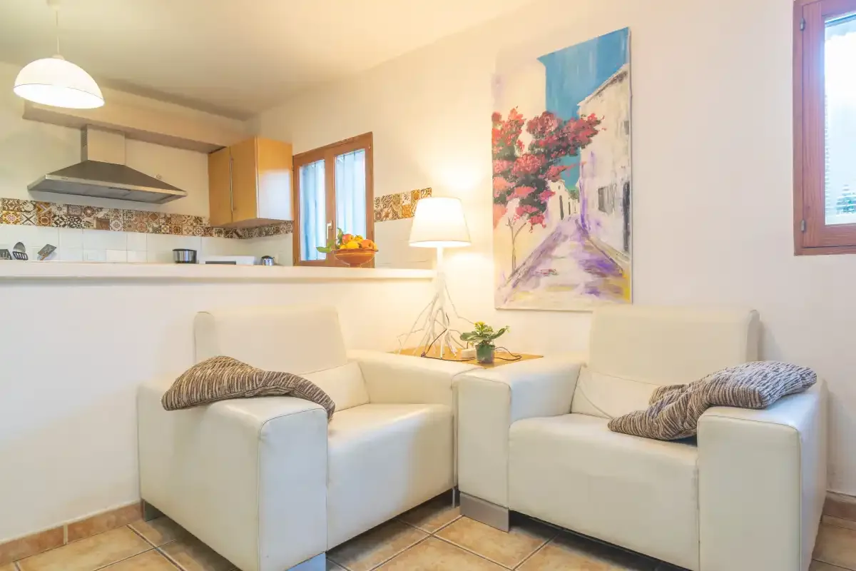 A bright living area with white seating, a lamp, and colorful wall art.