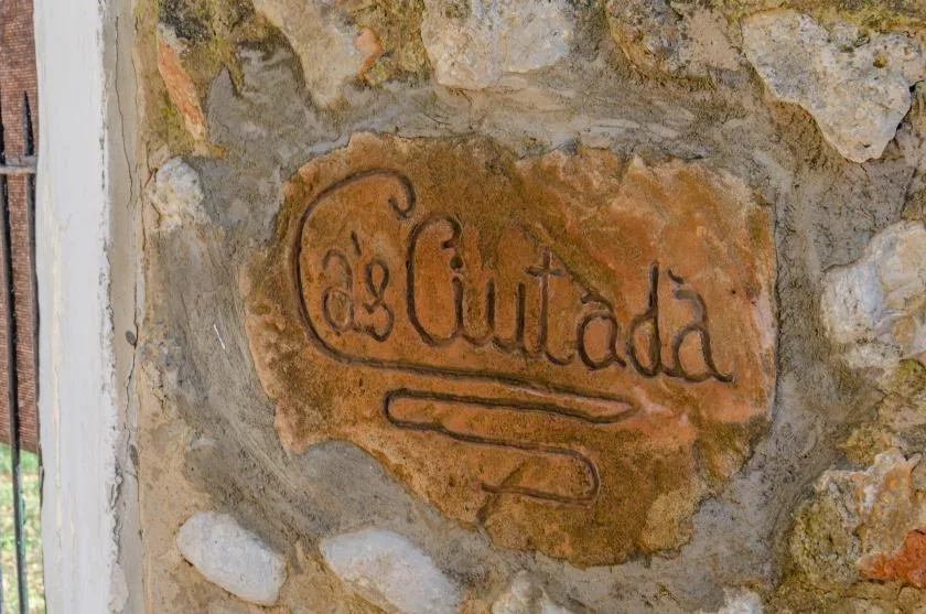 A stone wall features a carved plaque with decorative lettering.