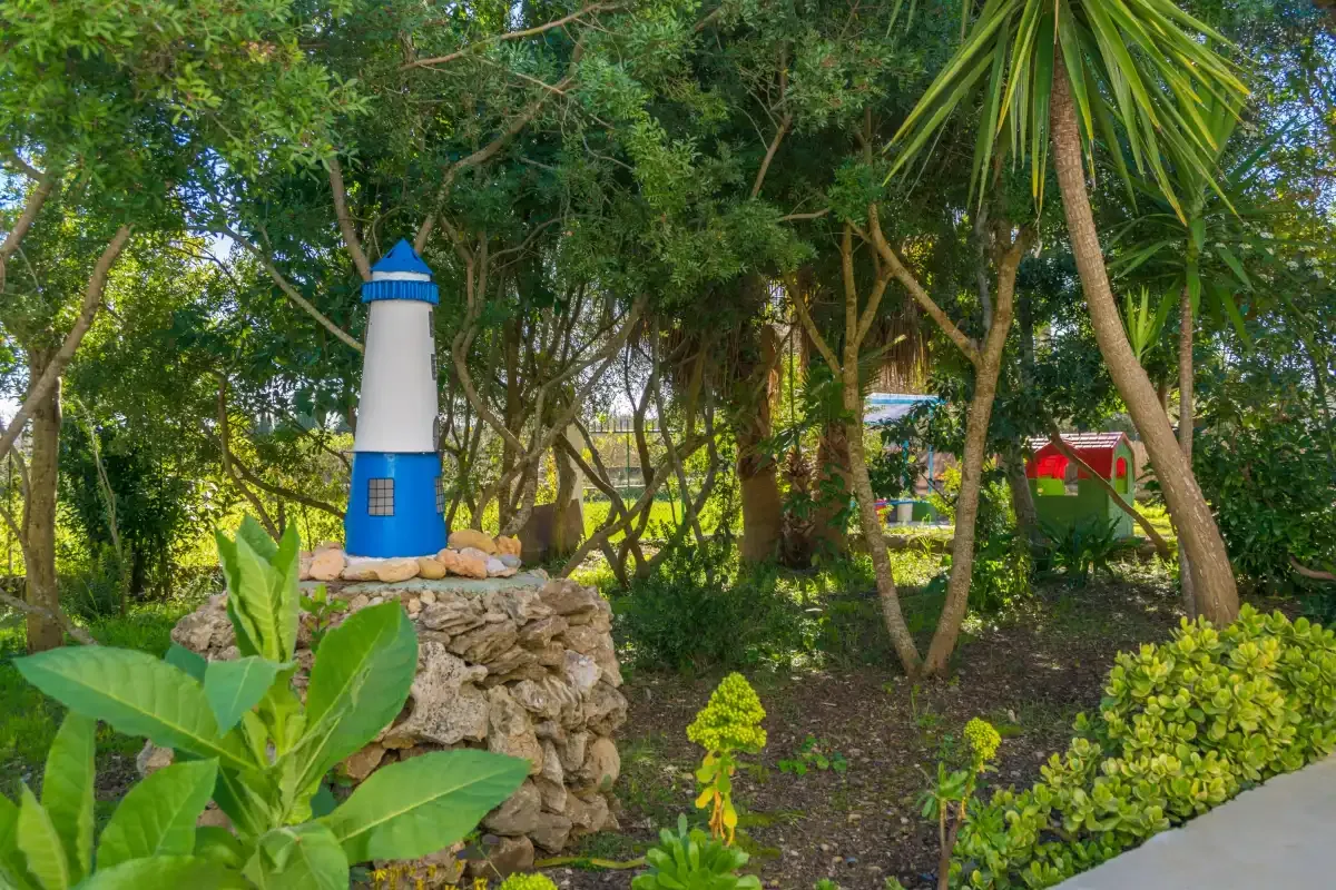 A landscaped garden with trees, shrubs, and a small decorative lighthouse.