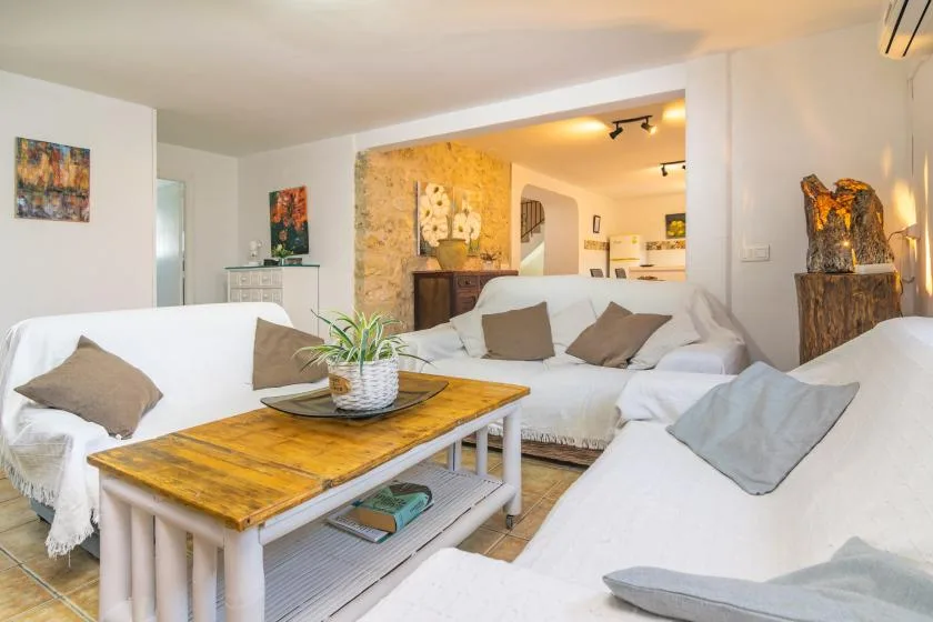 Living room with white seating, a wooden coffee table, and an open view into the kitchen.