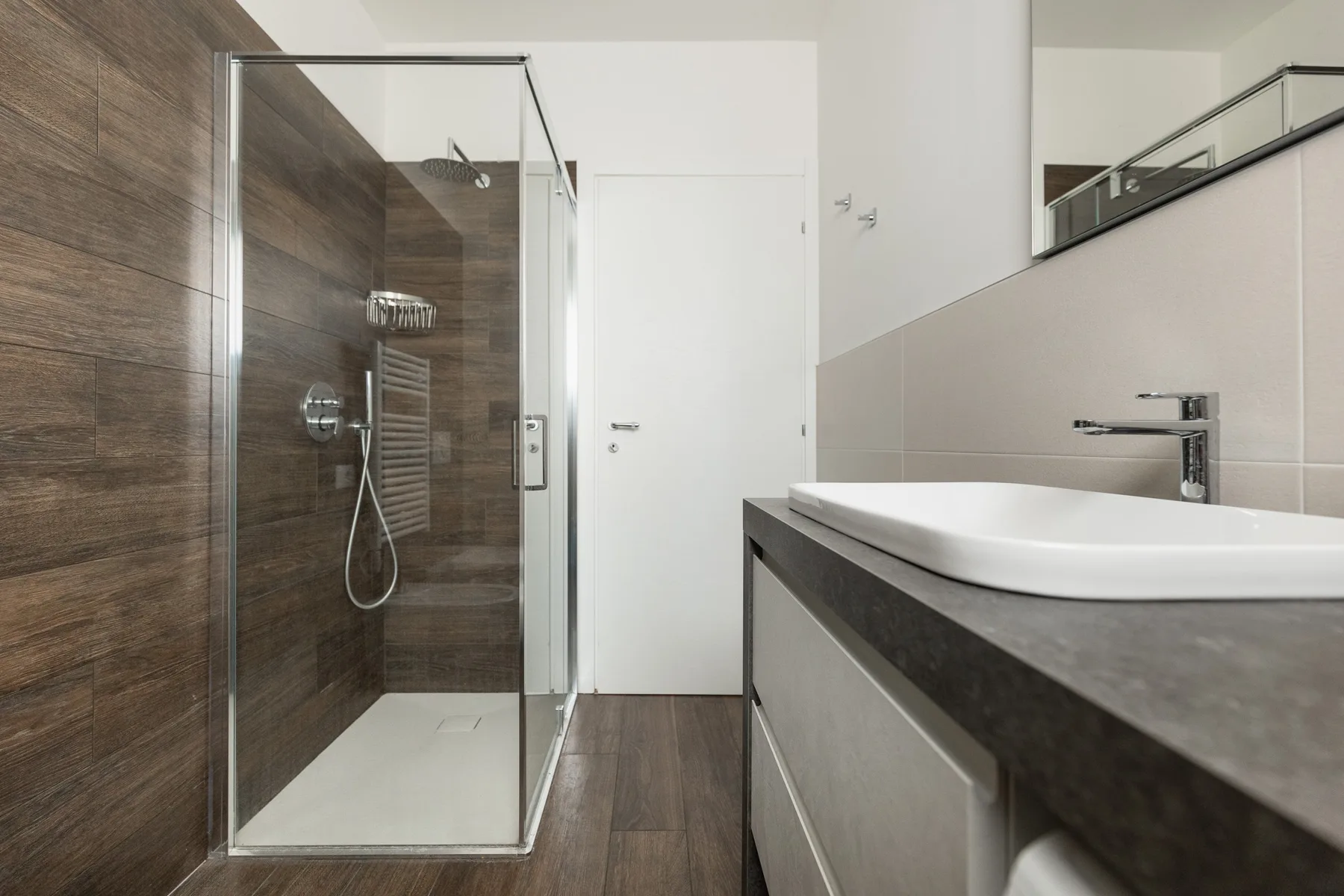 Un baño moderno con una ducha de vidrio y un lavabo amplio.