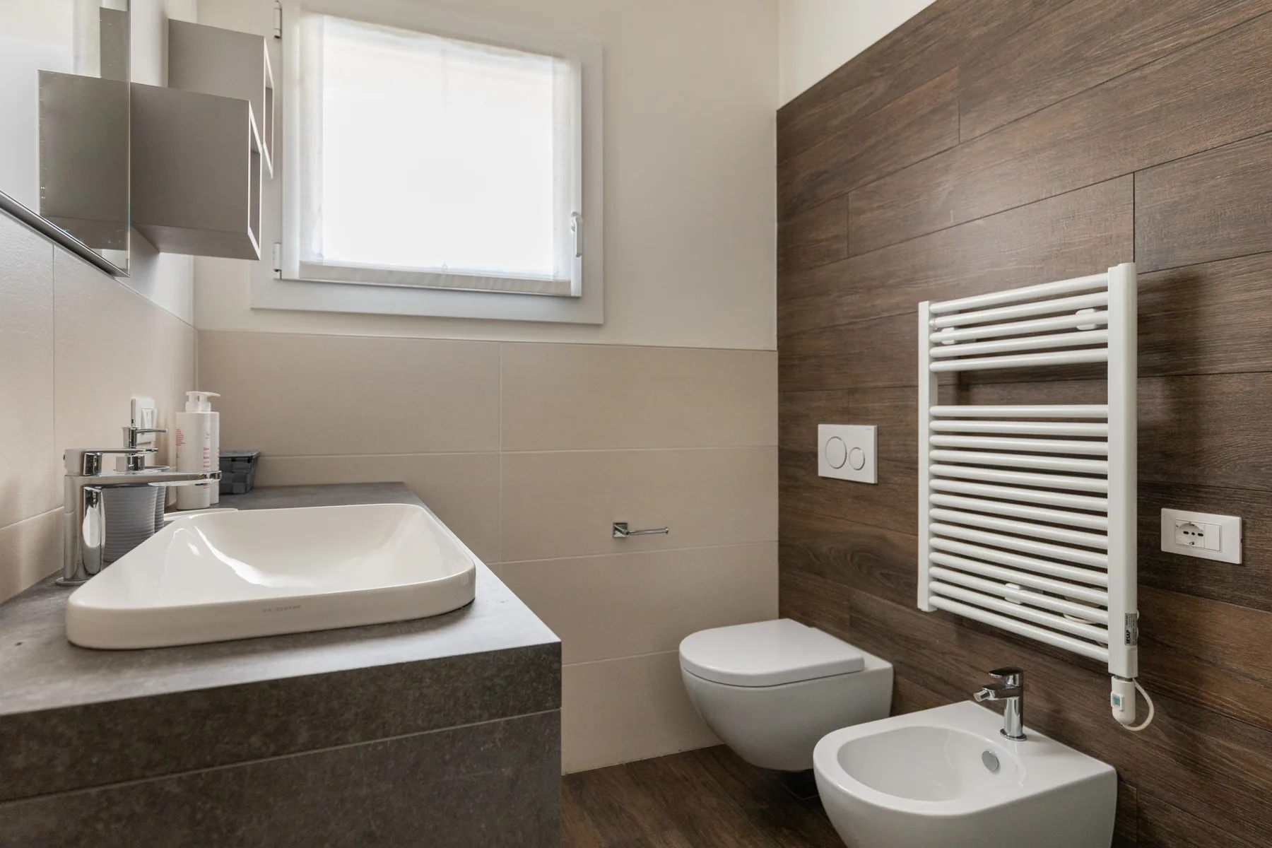 Un baño moderno con lavabo, inodoro y toallero calefactable.