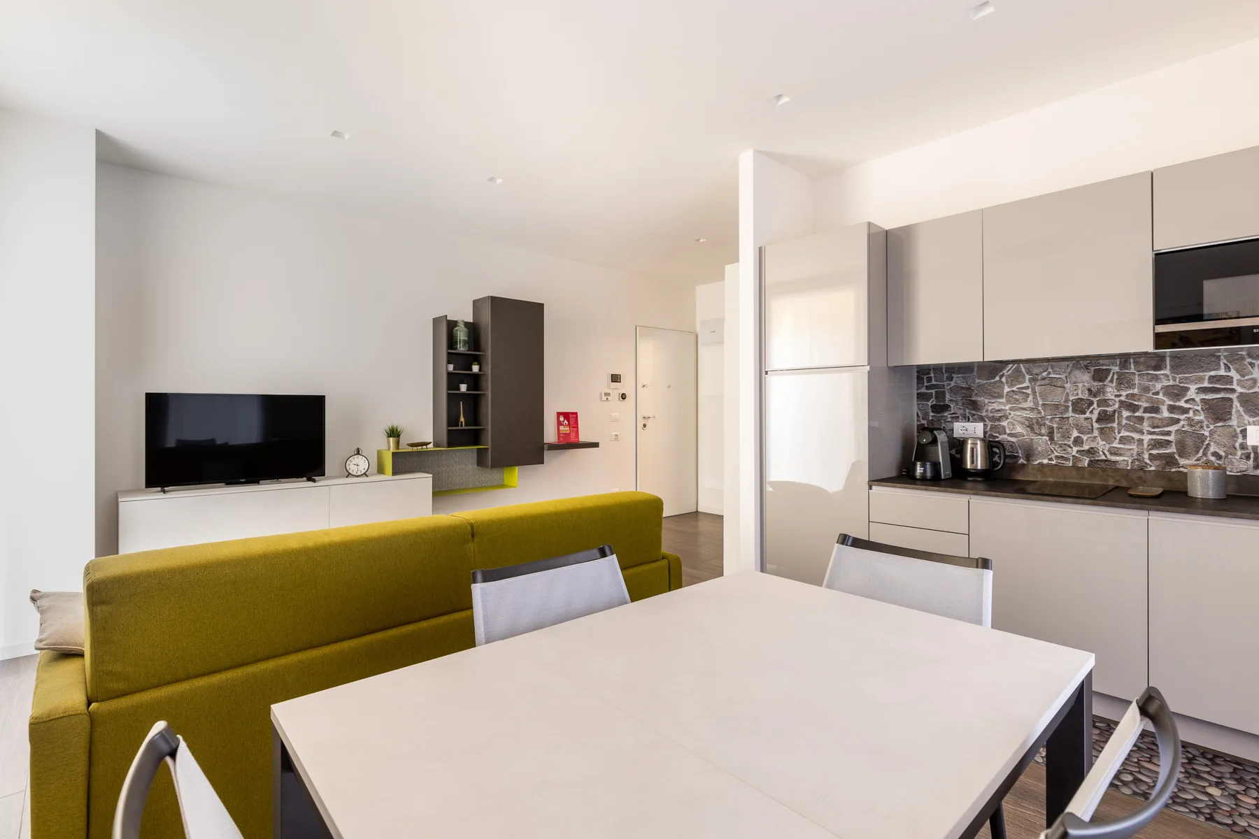 An open-plan living and kitchen area with a dining table and green seating.