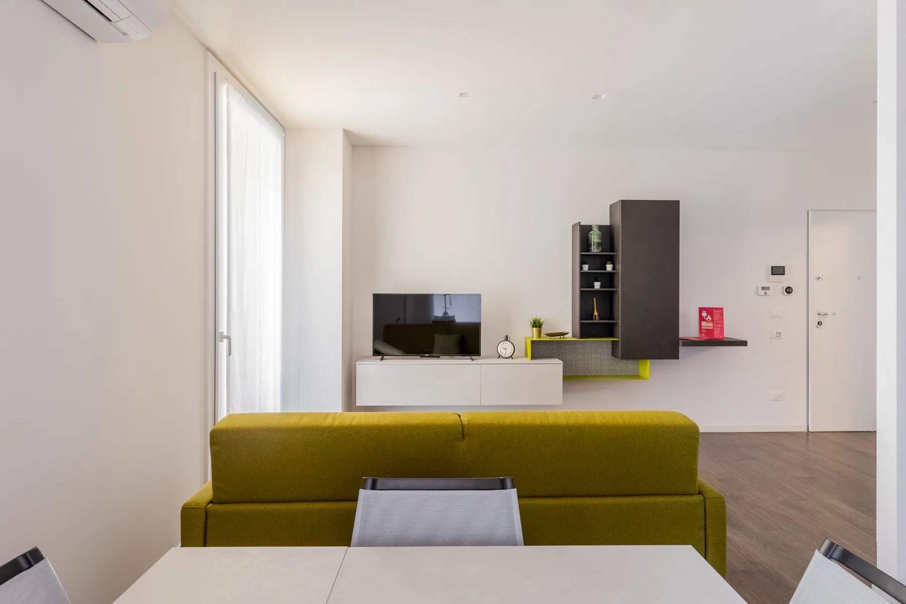 Una sala luminosa con un televisor y asientos de color mostaza.