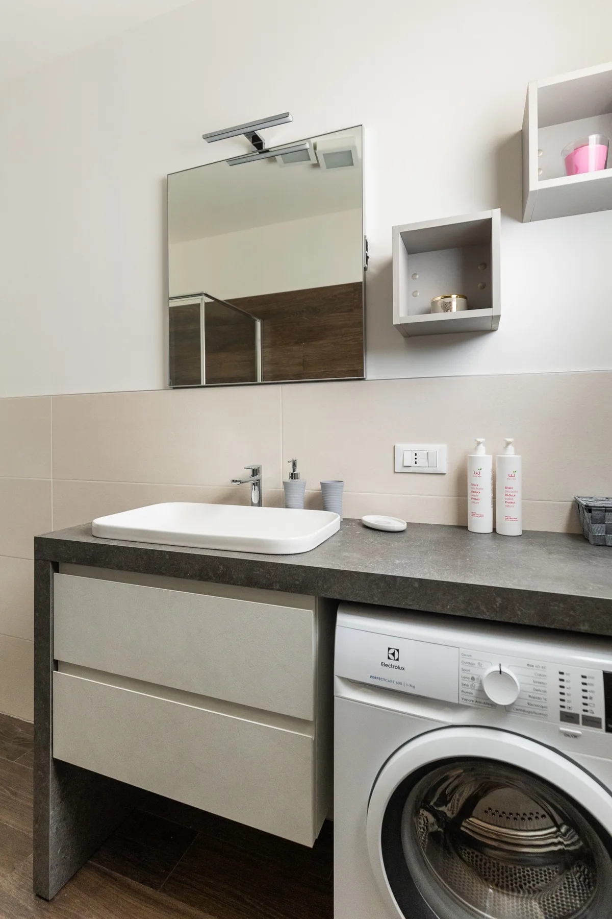 Un mueble de baño con lavabo y lavadora de carga frontal.