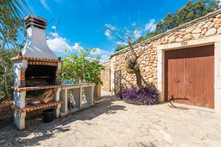 Un patio empedrado tiene una barbacoa exterior junto a un muro de piedra.