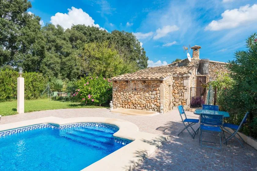 Una piscina al aire libre junto a un edificio de piedra y asientos en el patio.