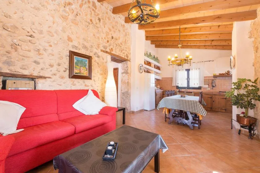 Una sala rústica con comedor, asientos rojos y una mesa bajo vigas de madera vistas.