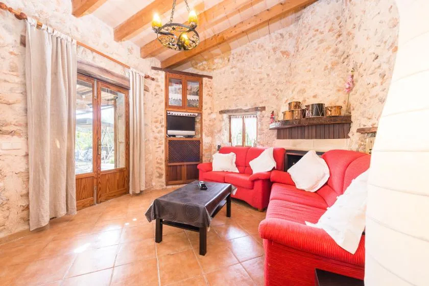 Una sala de estar con paredes de piedra, asientos rojos y una mesa de centro de madera.