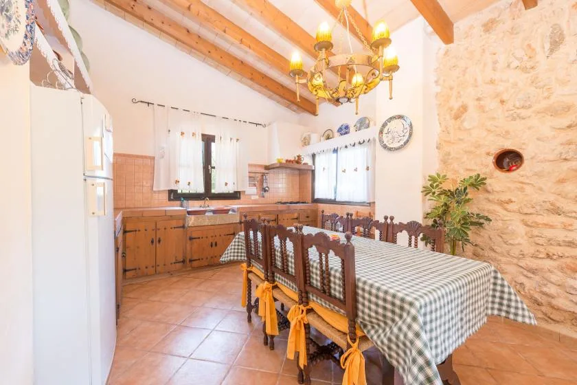 Una cocina rústica con comedor y una mesa larga bajo vigas de madera expuestas.