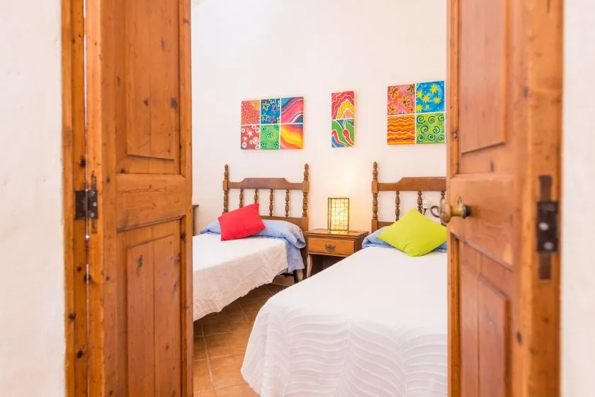 Un dormitorio con dos camas, una mesita de noche y cuadros coloridos en la pared.