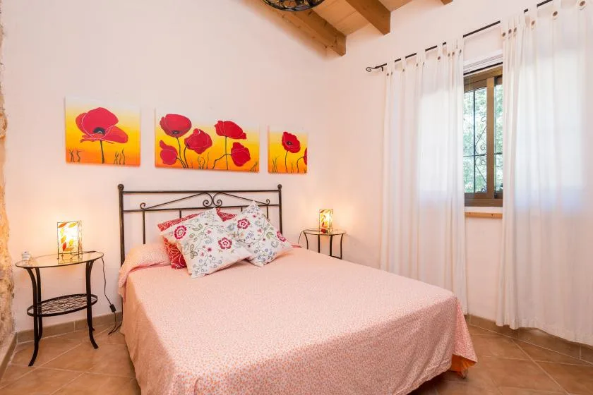 Un dormitorio con una cama doble bajo cuadros coloridos de amapolas.