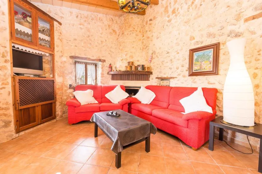 Una sala de estar con asientos rojos, un mueble de madera y paredes de piedra.