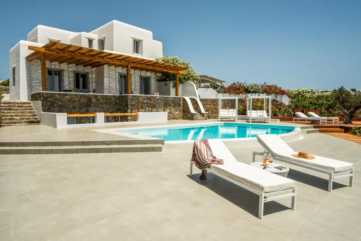 A modern villa beside a swimming pool, with loungers on the terrace.