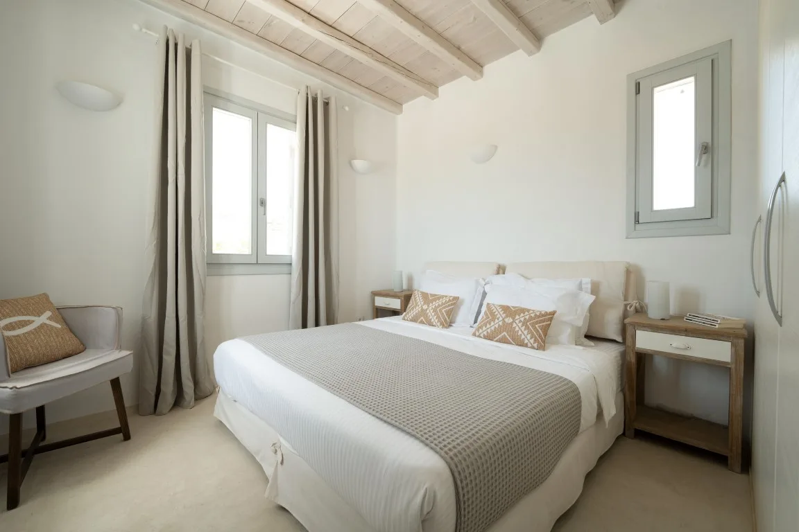 A bright bedroom with a double bed and windows.