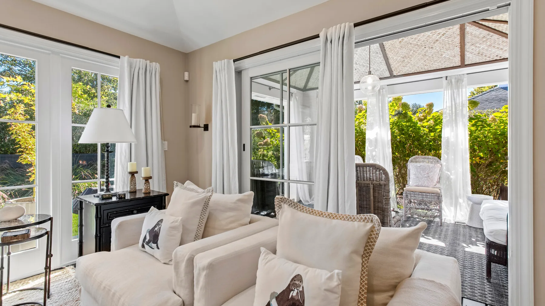 Una sala luminosa con asientos junto a grandes ventanas y una puerta de vidrio al patio.