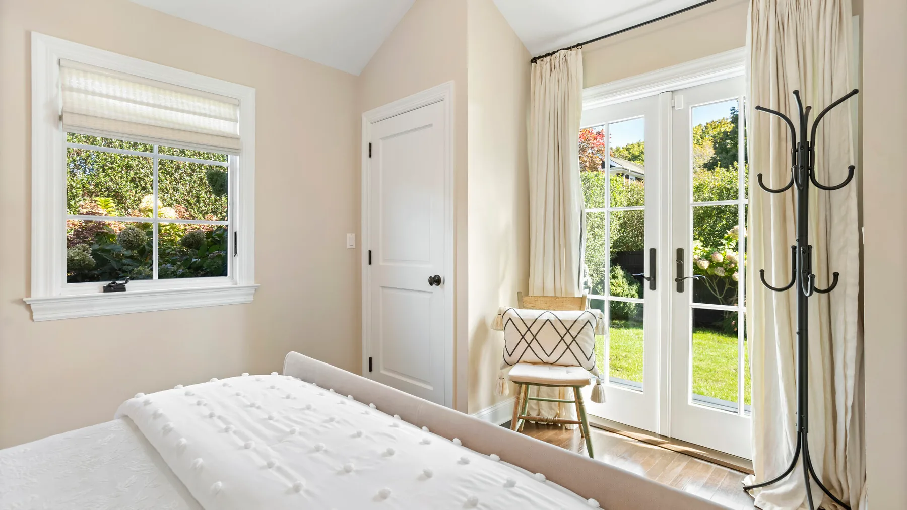 Un dormitorio luminoso con una cama junto a una ventana que da a la vegetación.