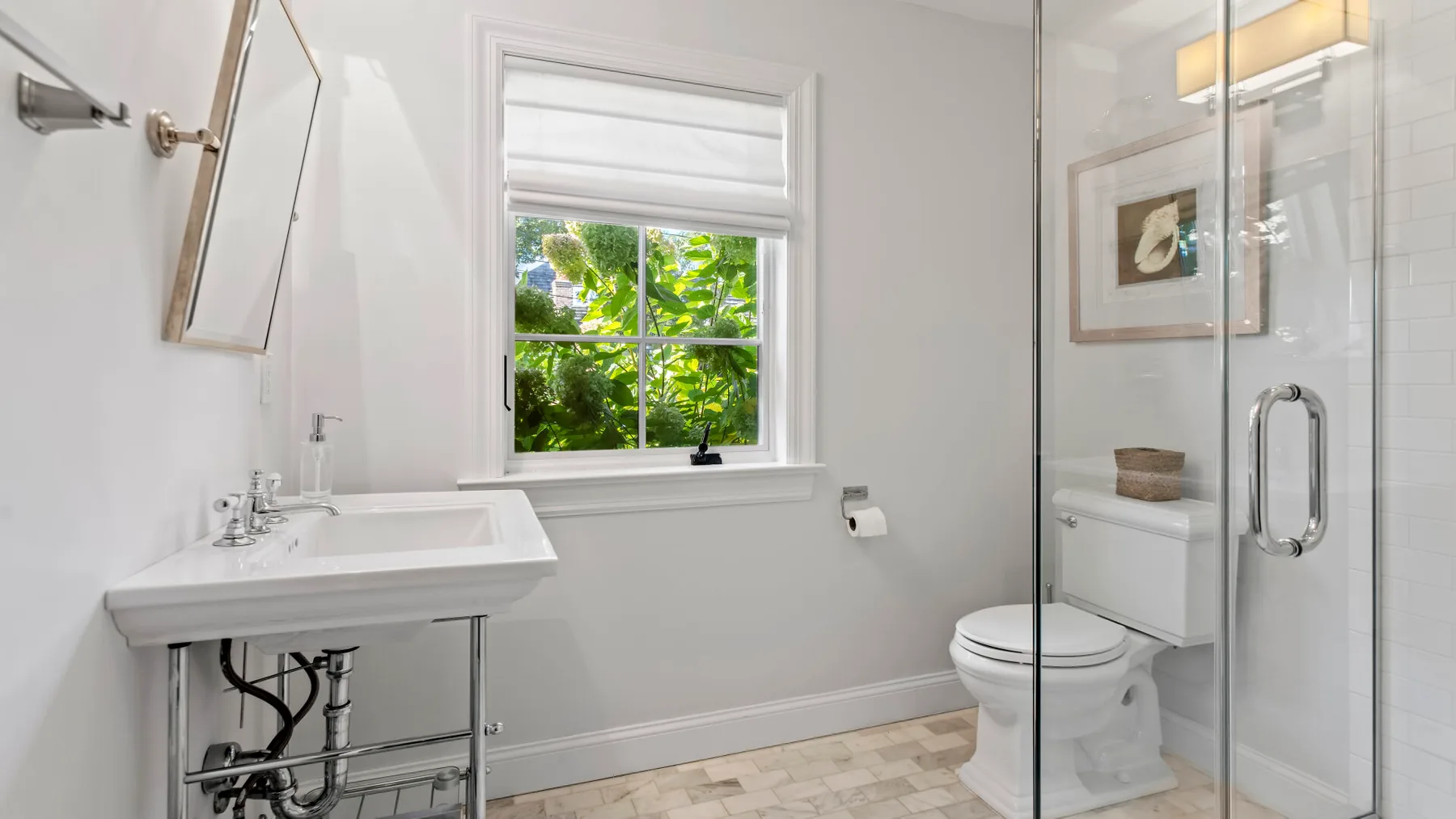 Un baño luminoso con lavabo, inodoro y ducha de cristal.