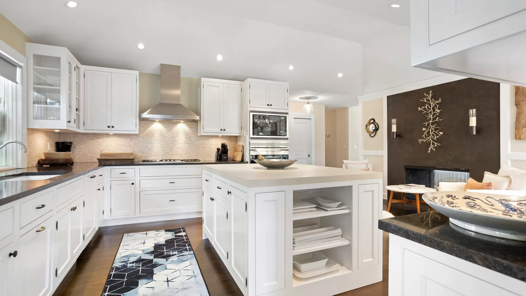 Una cocina blanca y luminosa con una isla central y estantes abiertos.