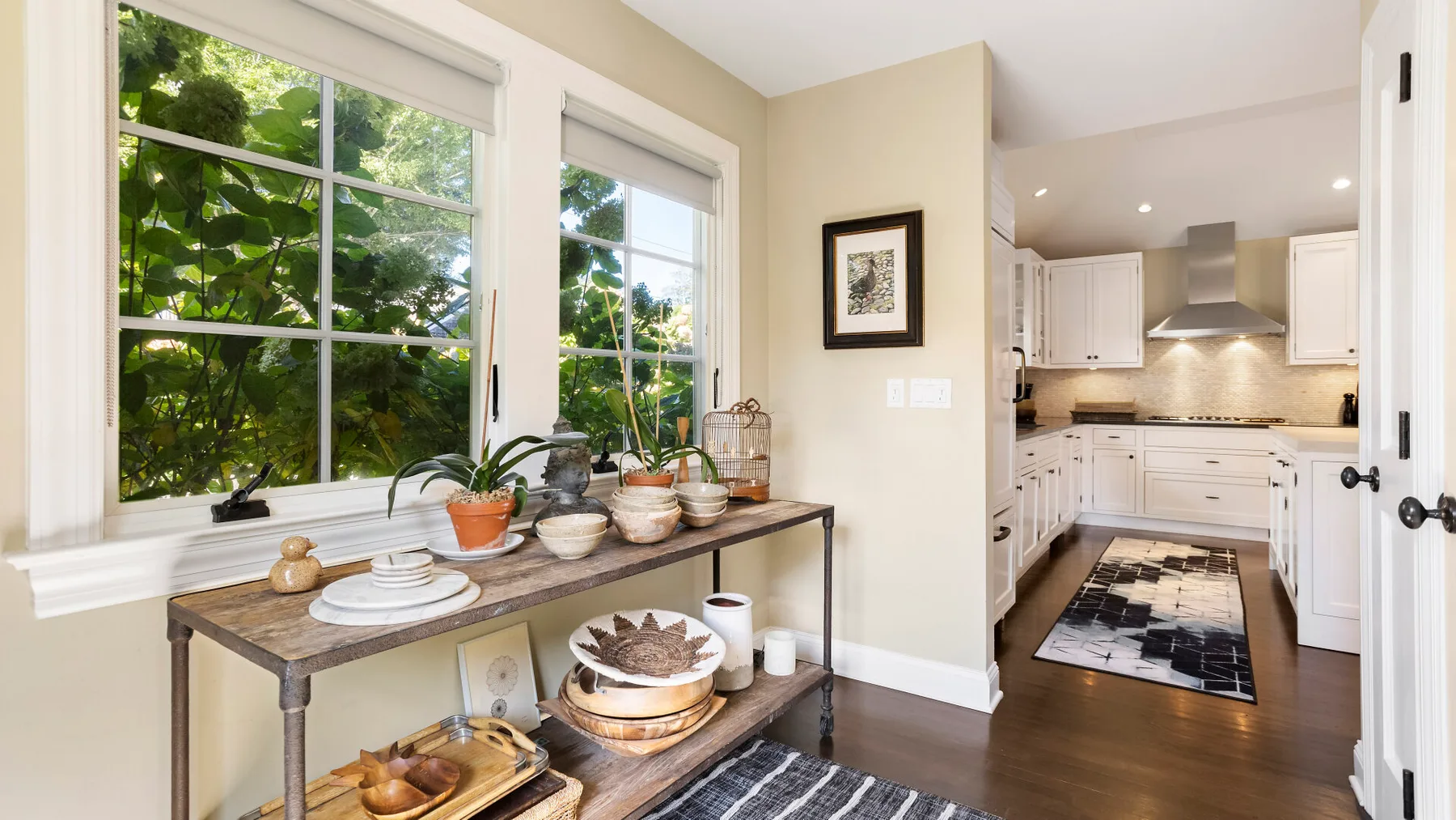 Una cocina luminosa junto a un rincón para comer, con grandes ventanas que dan a la vegetación.