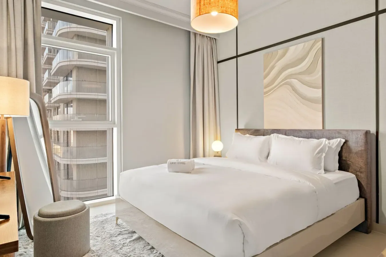 Un dormitorio luminoso cuenta con una cama bien tendida junto a una ventana grande.