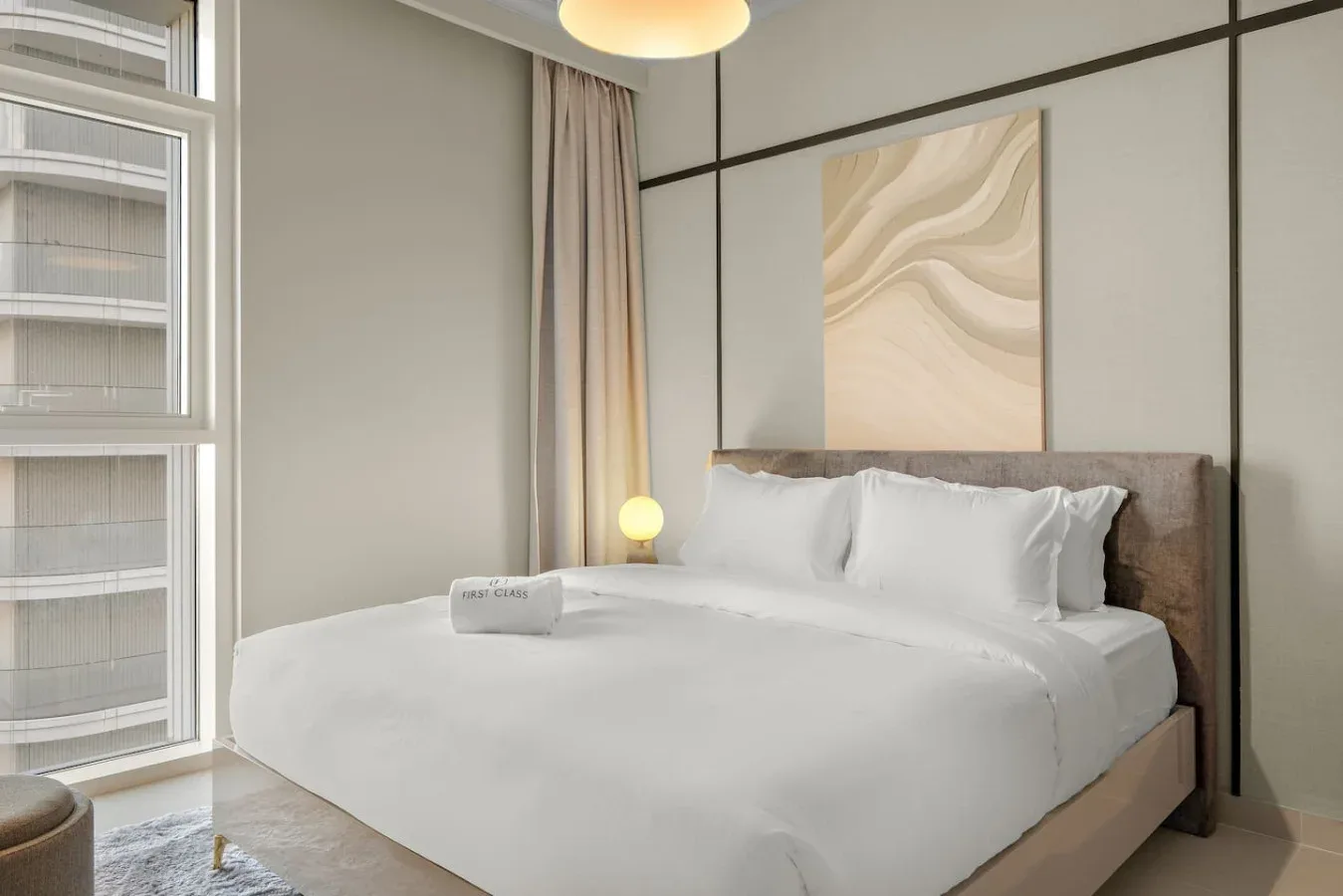Un dormitorio con una cama vestida con ropa de cama blanca y arte abstracto en la pared.