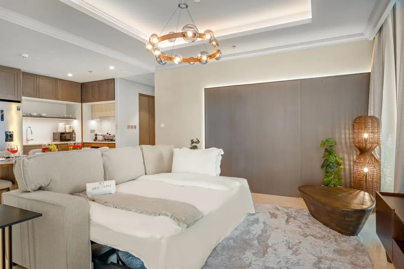 Dormitorio con una cama grande, una zona de asientos acolchada y una cocina al fondo.
