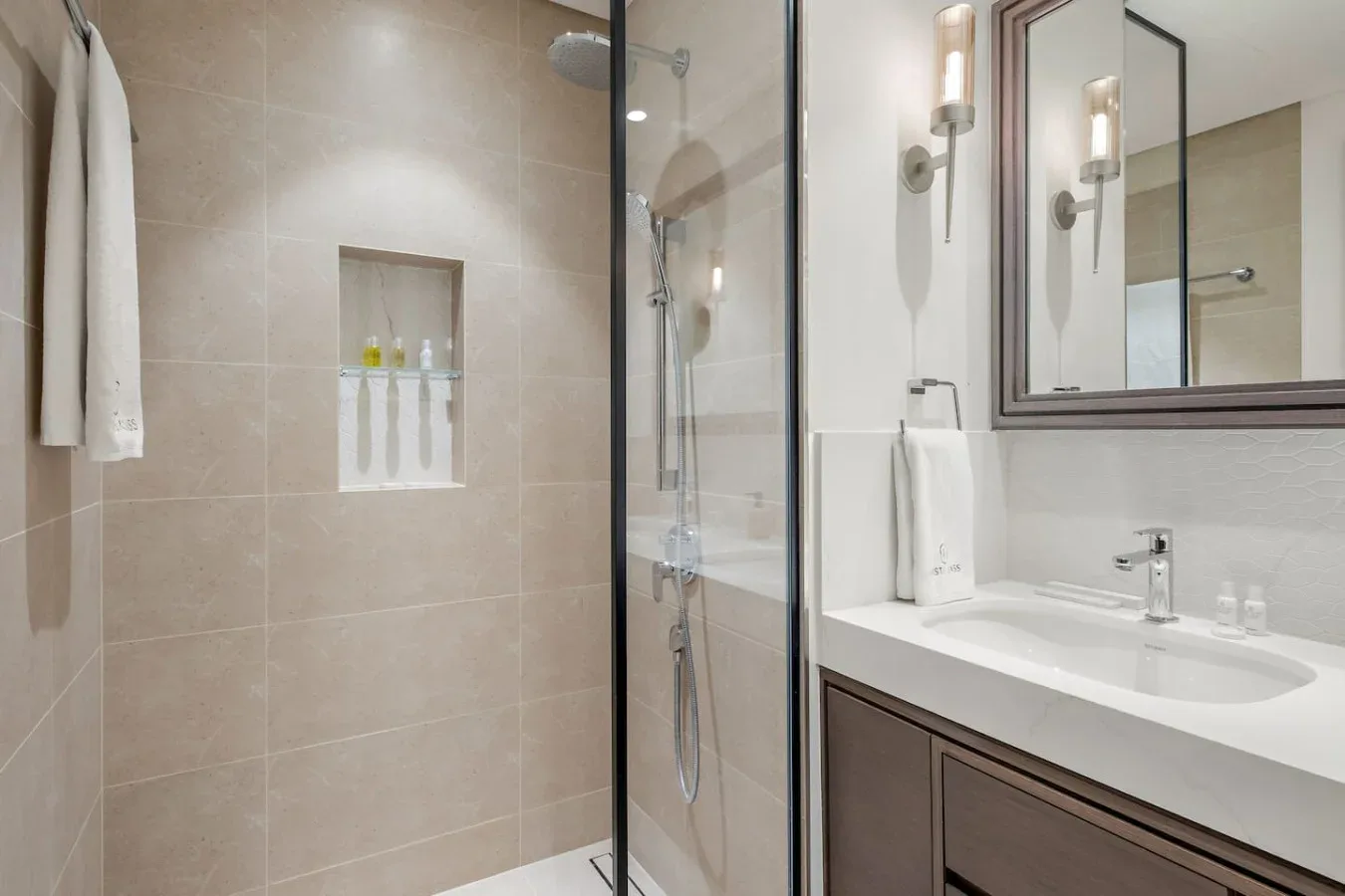 Un baño alicatado con ducha de vidrio y lavabo con mueble.