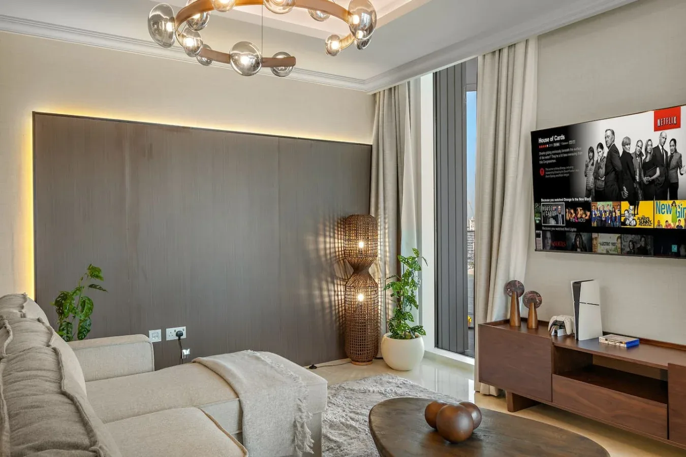 Una sala de estar moderna con asientos claros, una mesa baja y un televisor en la pared.