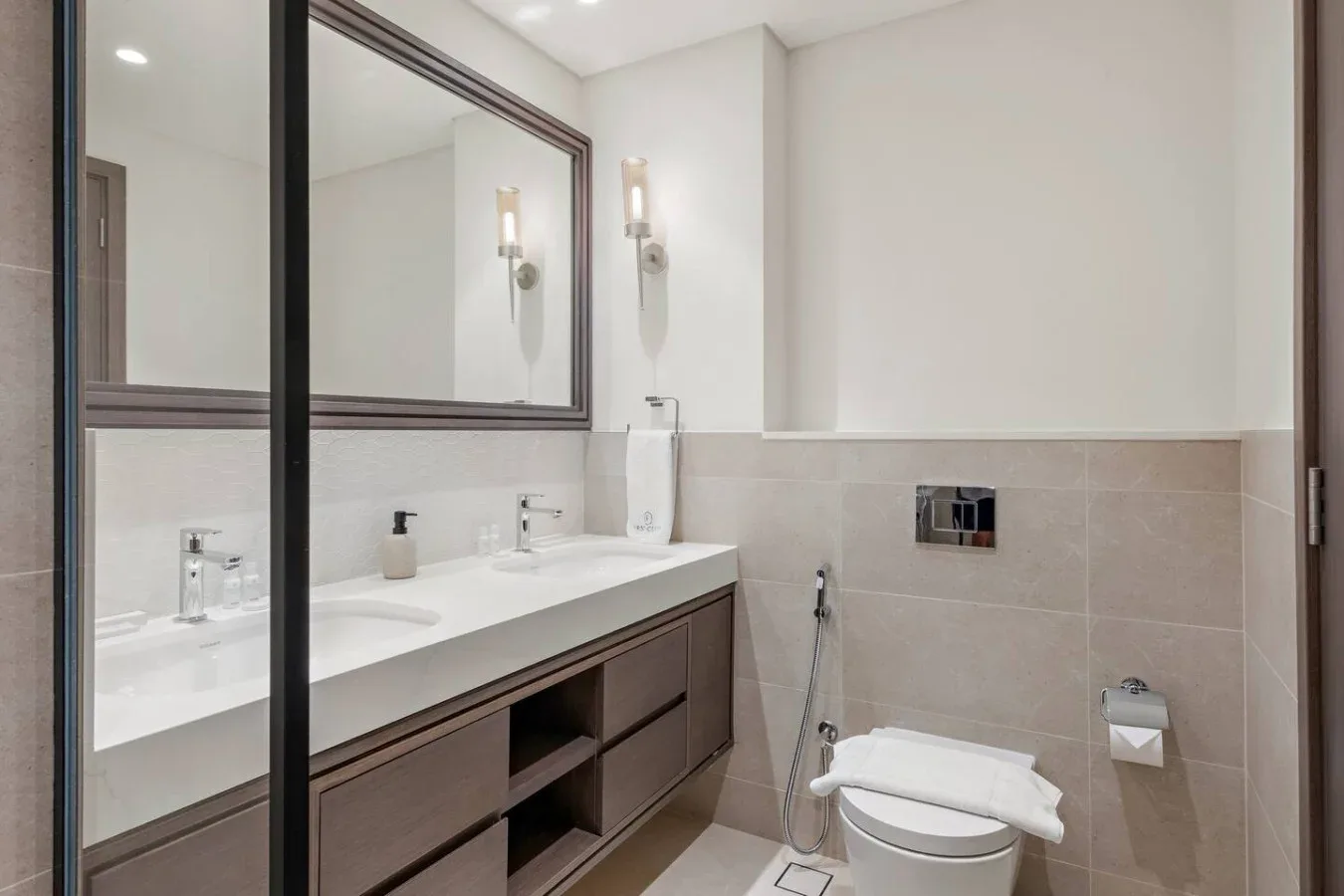 Un baño luminoso con un tocador largo, espejo de pared e inodoro.