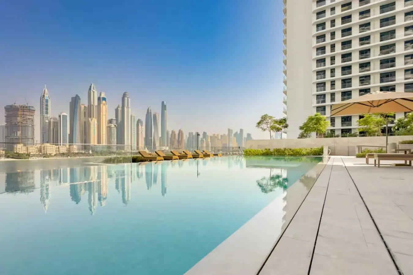 A rooftop pool overlooks a city skyline beside a paved deck.