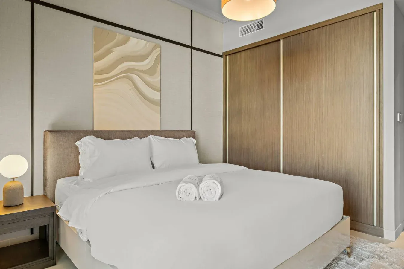 Un dormitorio con una cama bien tendida y arte abstracto en la pared.