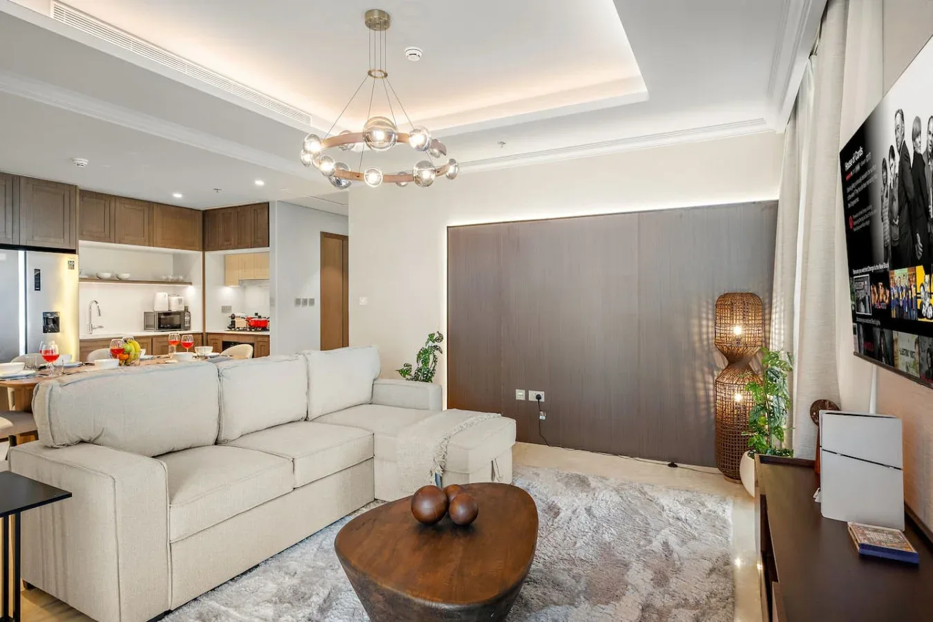 Una sala luminosa con una zona de asientos clara y una cocina contigua.