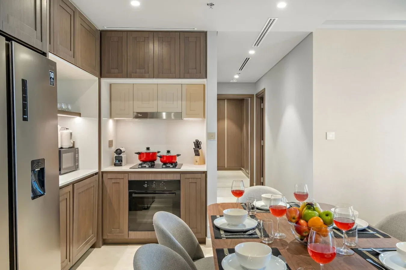 Una cocina moderna se abre a una mesa de comedor preparada con platos y bebidas de colores.
