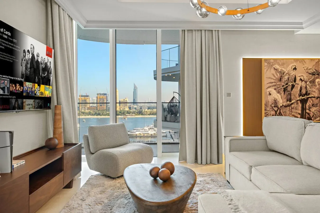 Una sala luminosa con asientos, una mesa baja y grandes ventanales con vistas al agua.