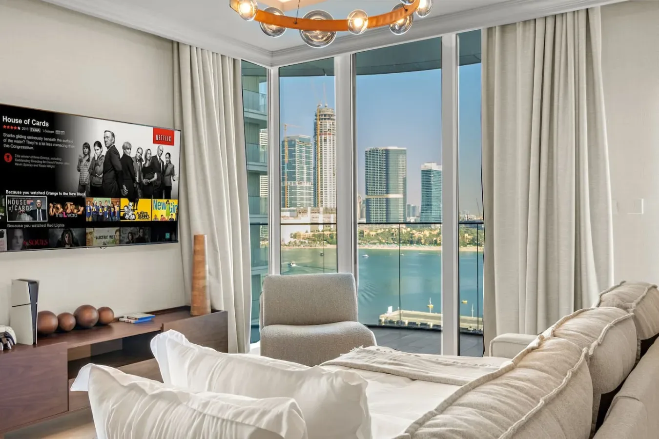 A bright living room with seating beside floor-to-ceiling windows overlooking the water and skyline.
