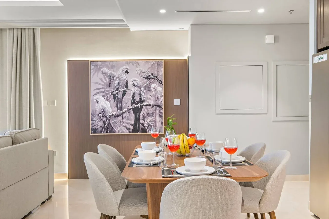 Un comedor con la mesa puesta y una obra enmarcada en la pared.
