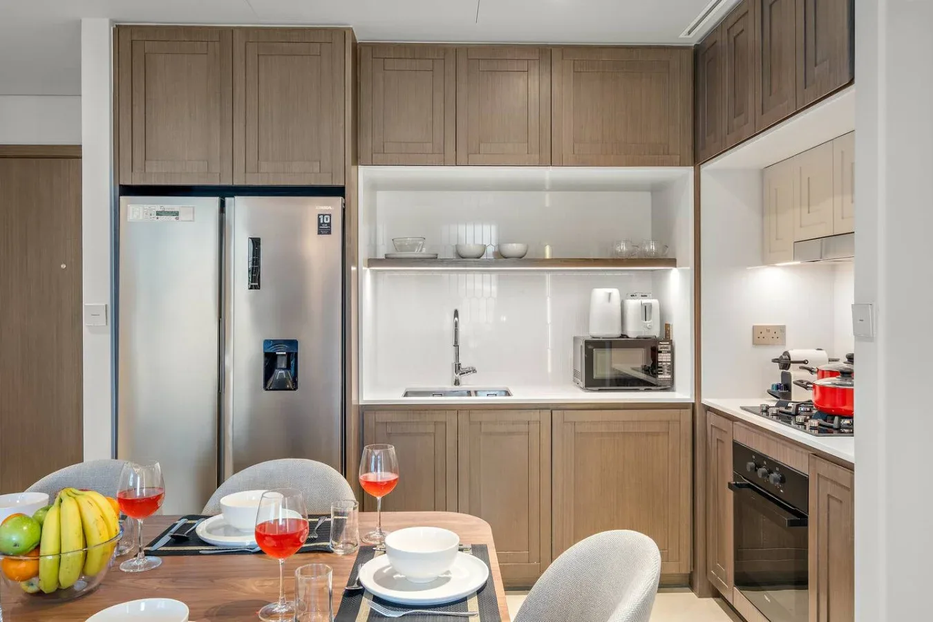 Una cocina moderna con gabinetes de madera, un refrigerador y una mesa de comedor.