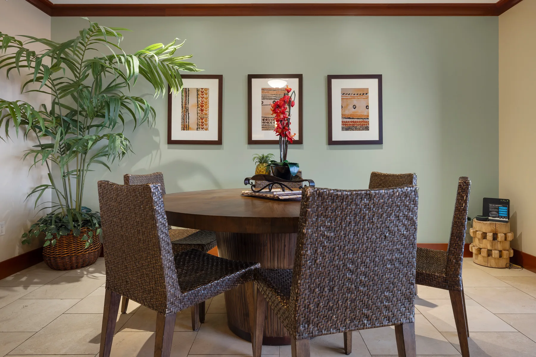Comedor con una mesa redonda, asientos tejidos y cuadros enmarcados en la pared.