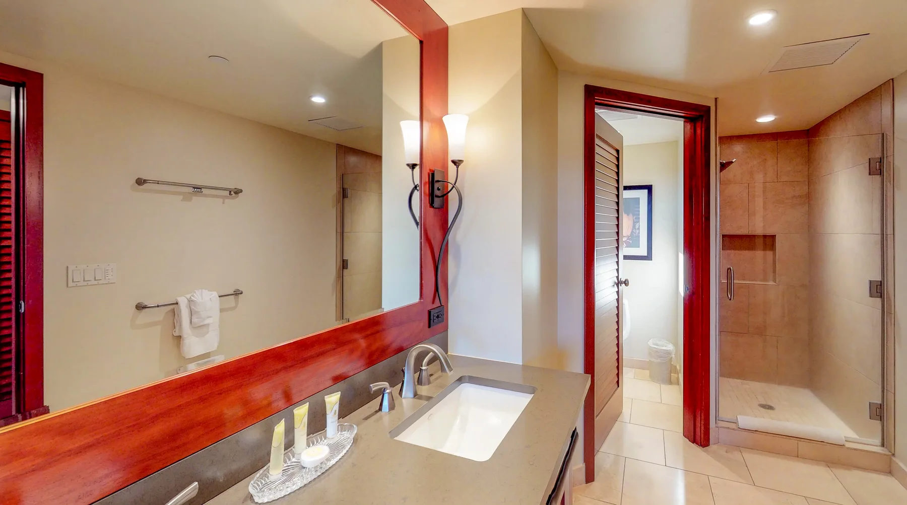 Un lavabo con espejo está junto a una ducha de vidrio en el baño.