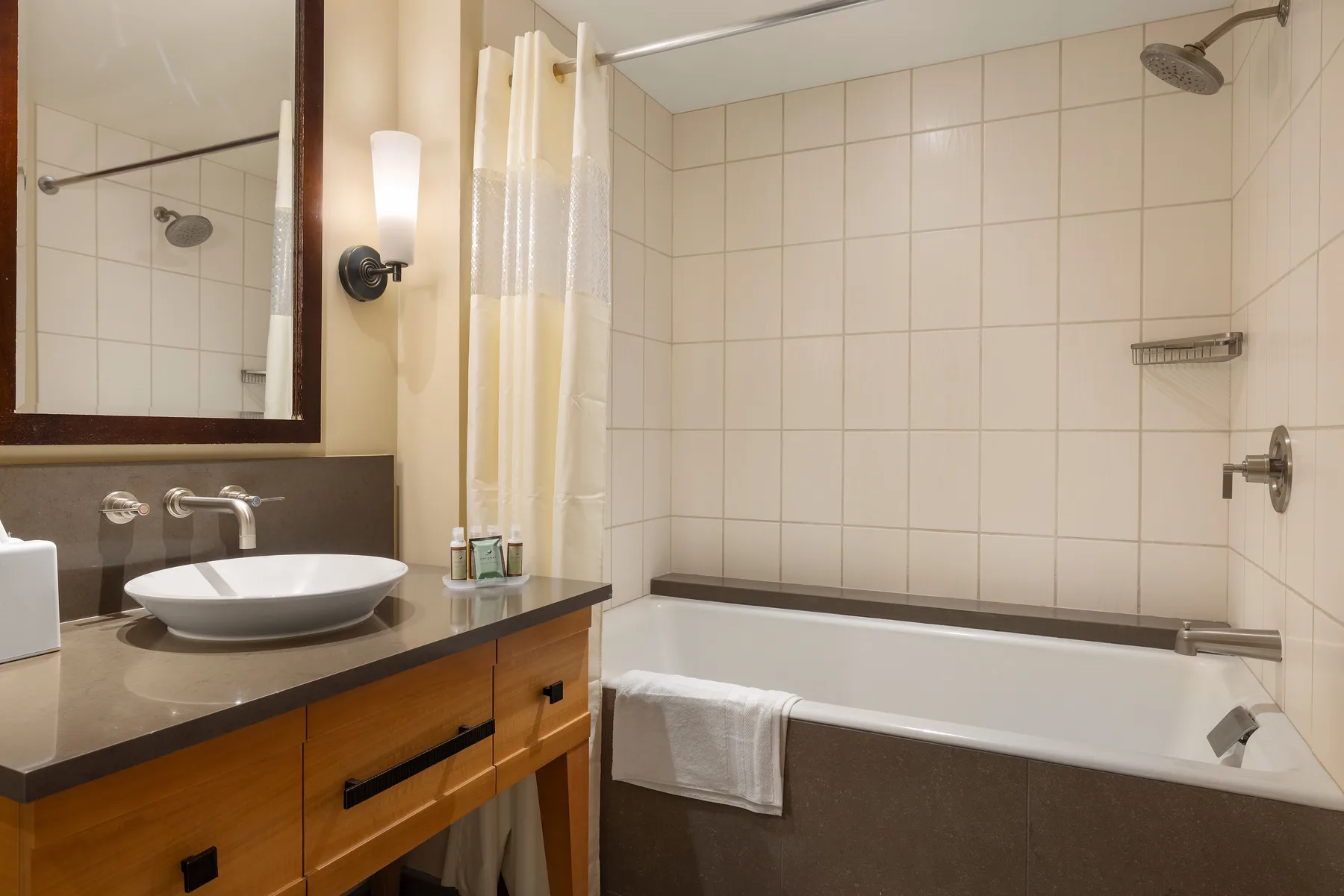 Un baño con bañera, ducha y lavabo junto a un tocador con espejo.