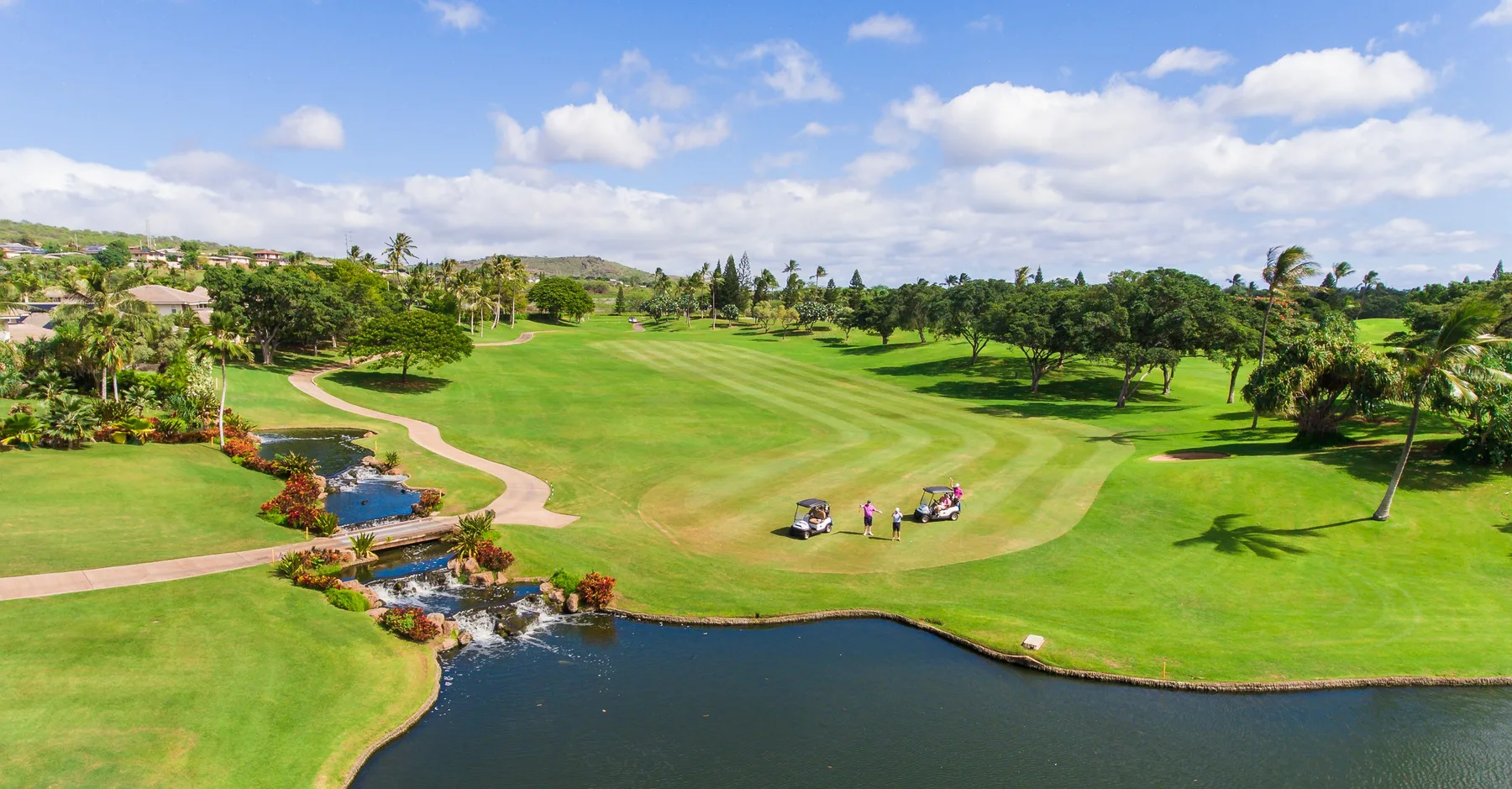 Un campo de golf ajardinado se extiende junto a un estanque.