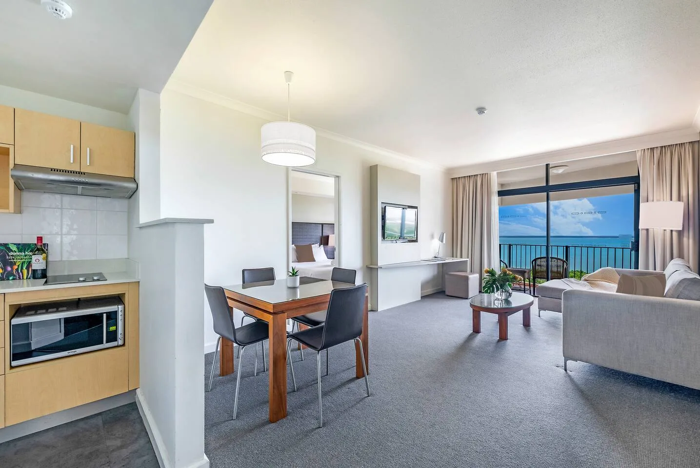 An open-plan living and dining area with a kitchen and ocean views through large windows.