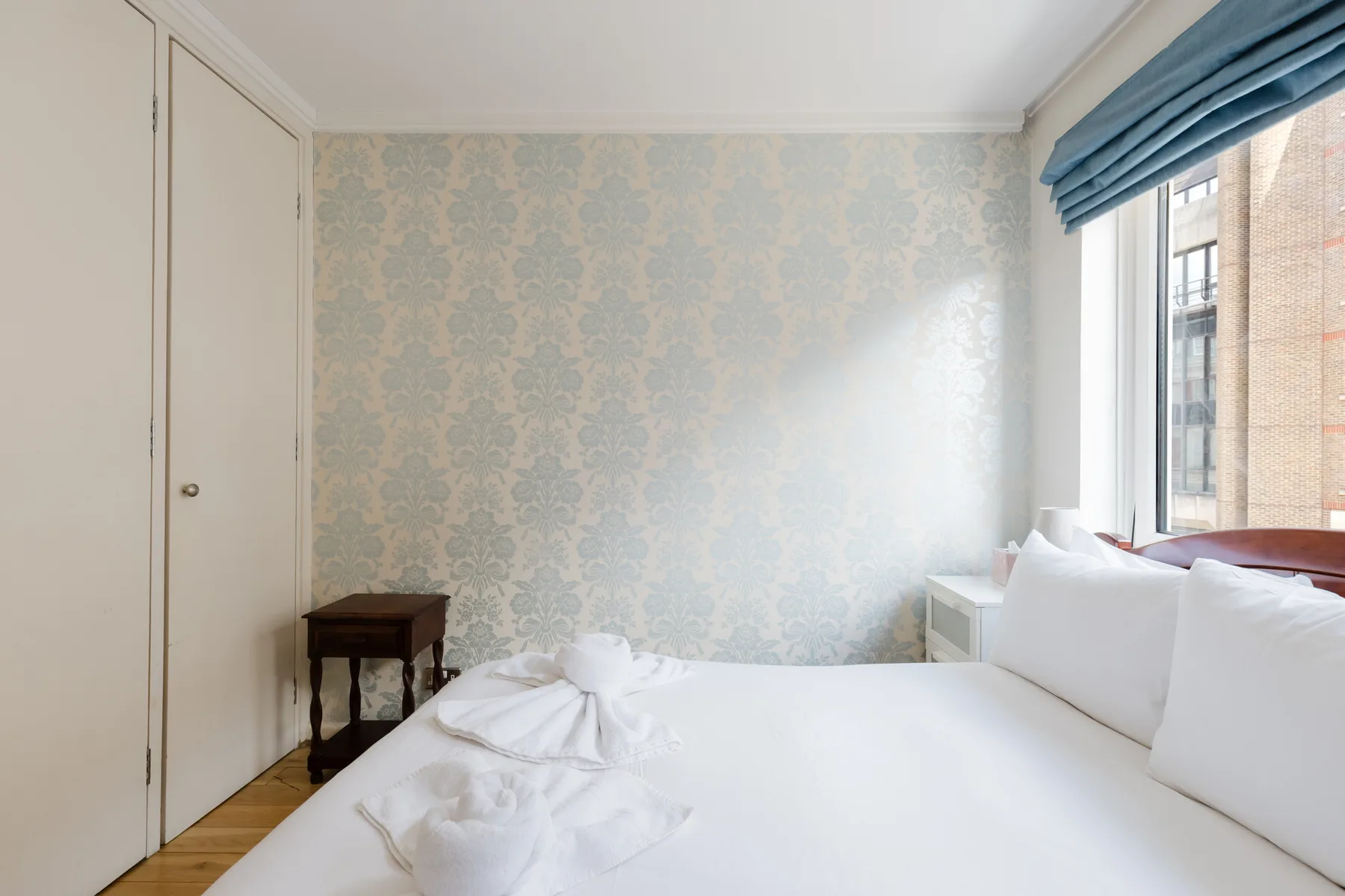 A bedroom with white bedding and a large window.